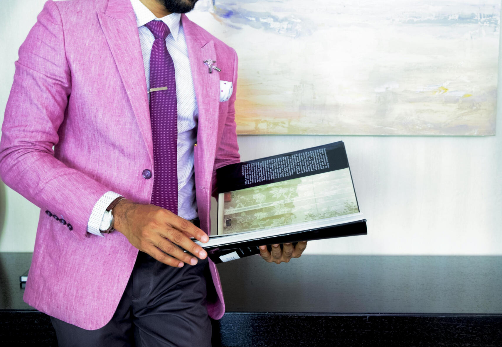 A man in a pink suit is holding a book